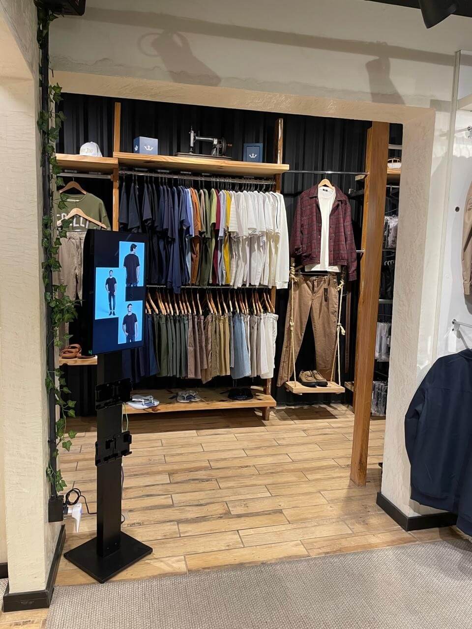 Exposição de camisetas e calças com painel digital ao lado